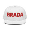 The BRADA fOR LIFE. snapback cap in WHITE, featuring bold red BRADA, combines style with function through its flat brim and small ventilation holes, offering a sleek look accented by a GREY under visor.