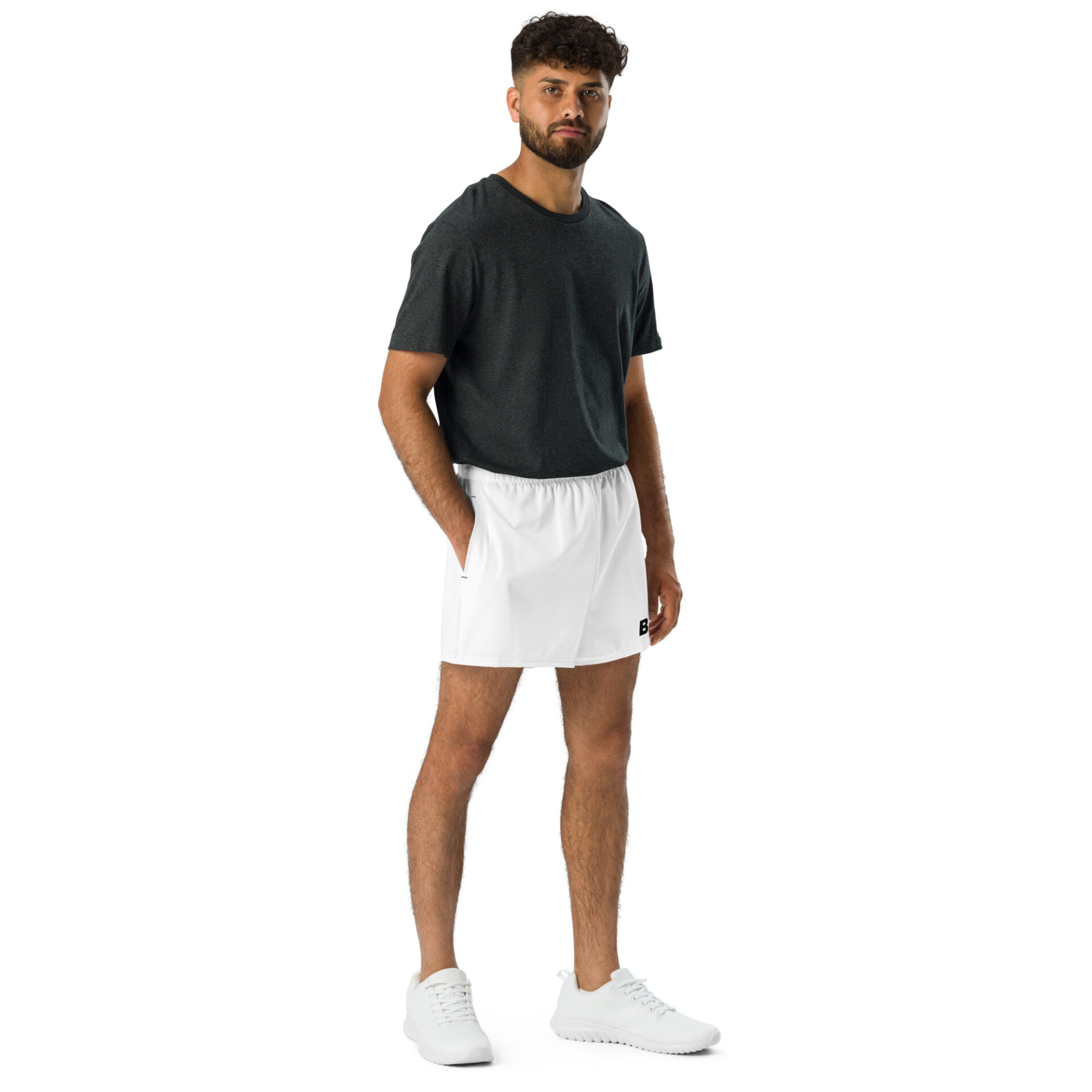 A man poses against a white background, showcasing the latest in sportswear: a dark gray t-shirt, BAAS Athletic Shorts in crisp white, and sleek white sneakers. His relaxed arms, curly hair, and beard complete the effortless BAAS look. A man poses against a white background, showcasing the latest in sportswear: a dark gray t-shirt, BAAS Athletic Shorts in crisp white, and sleek white sneakers. His relaxed arms, curly hair, and beard complete the effortless BAAS look.