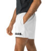 A person in white BAAS Athletic Shorts, adorned with BAAS on one leg, stands casually with a hand in their pocket, paired with a dark gray shirt against a plain white background. A person in white BAAS Athletic Shorts, adorned with BAAS on one leg, stands casually with a hand in their pocket, paired with a dark gray shirt against a plain white background.