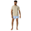 A man with curly hair and a beard stands barefoot against a white background, wearing a beige t-shirt and MJL Athletic Shorts in light blue with the MJL logo on the left leg. A man with curly hair and a beard stands barefoot against a white background, wearing a beige t-shirt and MJL Athletic Shorts in light blue with the MJL logo on the left leg.