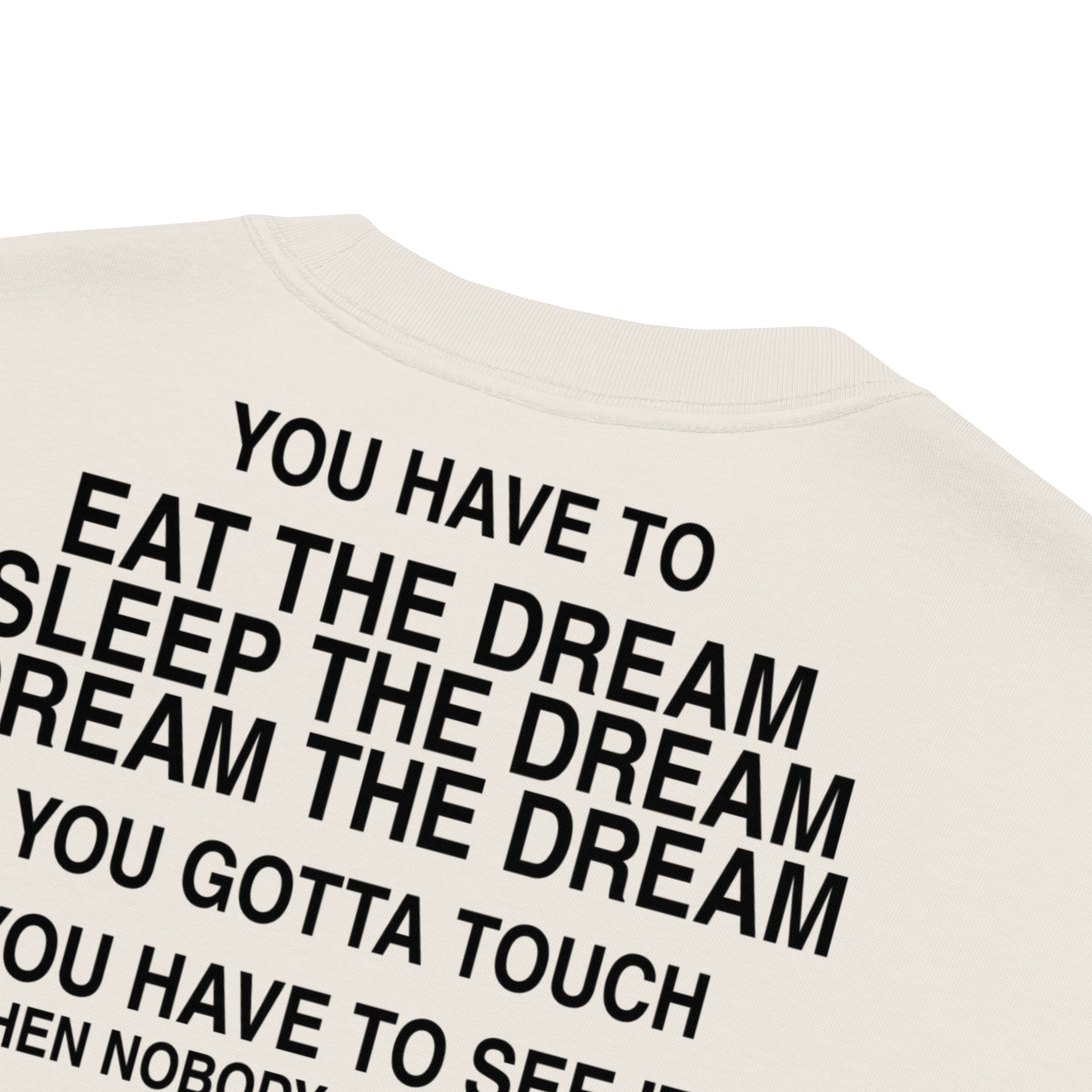 An oversized faded t-shirt in a cream color, featuring bold black text that says: YOU HAVE TO EAT THE DREAM, SLEEP THE DREAM, DREAM THE DREAM, YOU GOTTA TOUCH, YOU HAVE TO SEE IT.
